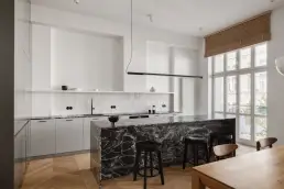 Kuchnia z białą zabudową, wyspą z czarnego granitu, białymi kafelkami zellige i widokiem na balkon w warszawskiej kamienicy