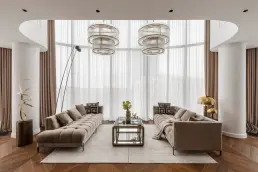 Dwie sofy naprzeciwko przeszklonej ściany z designerskimi żyrandolami – sesja fotograficzna wnętrz apartamentu