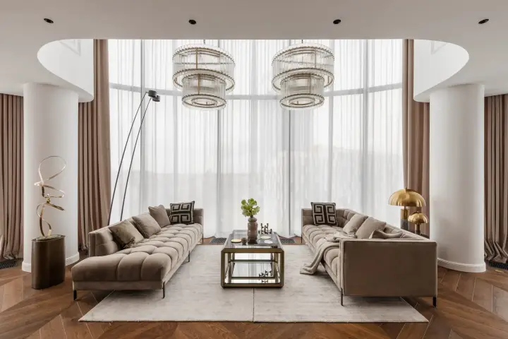 Dwie sofy naprzeciwko przeszklonej ściany z designerskimi żyrandolami – sesja fotograficzna wnętrz apartamentu