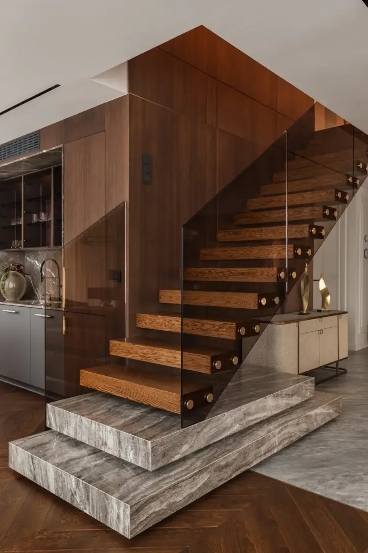 Schody wspornikowe z dębowymi stopniami, szklaną balustradą i marmurową podstawą – detal architektoniczny apartamentu