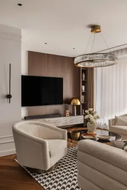 Zabudowa telewizyjna z forniru z mosiężnymi wstawkami i fotel bouclé – zdjęcia wnętrz luksusowego apartamentu