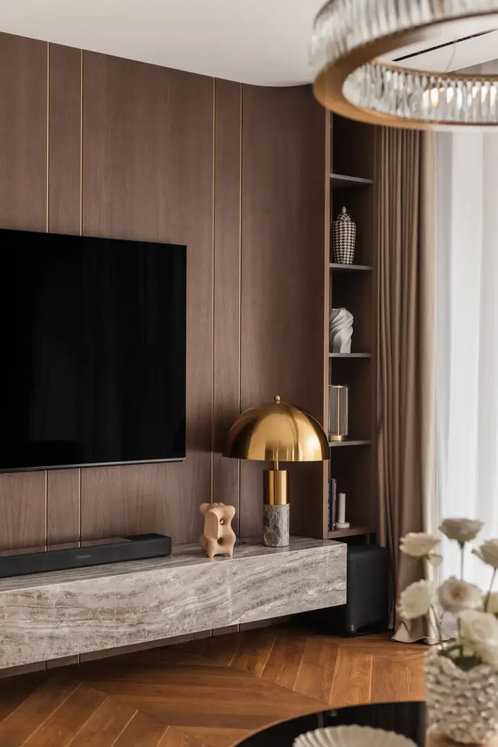 Zabudowa TV z forniru dębowego ze złotymi listwami i lampą kloszową – zdjęcia wnętrz apartamentu
