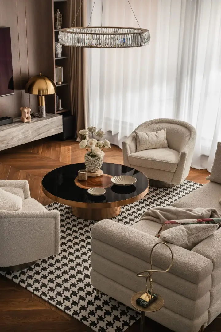 Strefa wypoczynkowa z okrągłym stolikiem kawowym, fotelami bouclé i dywanem w pepitkę – sesja fotograficzna wnętrz apartamentu