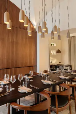 restauracja Muro Rzeszów — nakryty stół przy orzechowej zabudowie z lustrem i ceramicznymi lampami wiszącymi