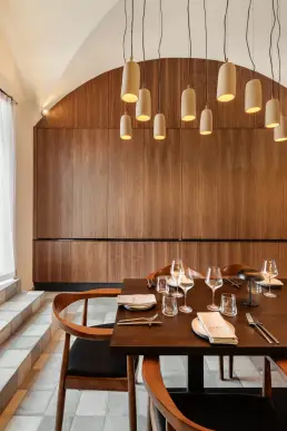 restauracja Muro Rzeszów — stolik pod łukowym sklepieniem przy orzechowej ścianie z podświetlanymi kinkietami