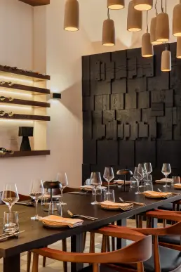 restauracja Muro Rzeszów — nakryty stół z kieliszkami na tle podświetlanego regału na wino i ściany z drewnianych bloków