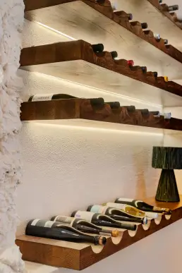 restauracja Muro Rzeszów — detal podświetlanego regału na wino z drewnianych desek na kamiennej ścianie