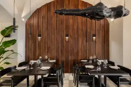 restauracja Muro Rzeszów — stoliki przy łukowej ścianie z drewnianych desek i rzeźbiarską lampą z ciemnego drewna
