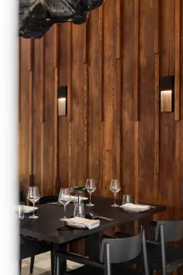 restauracja Muro Rzeszów — detal nakrycia stołu pod rzeźbiarską lampą z ciemnego drewna na tle lameli