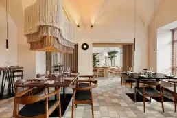 restauracja Muro Rzeszów — sala z makramową lampą z frędzlami, widokiem na dalszą część z drzewkiem oliwnym i sznurowymi zasłonami
