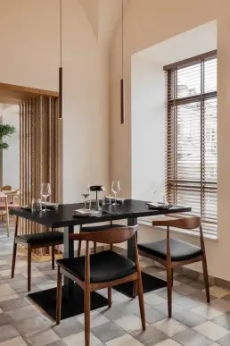 restauracja Muro Rzeszów — stolik przy oknie z drewnianymi żaluzjami, sznurowa ścianka działowa i minimalistyczne lampy wiszące