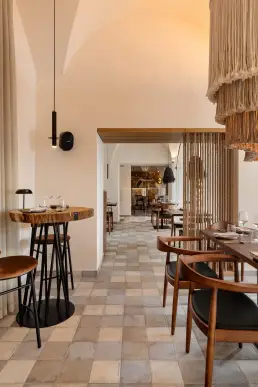 restauracja Muro Rzeszów — przejście między salami ze stolikiem barowym, sznurową ścianką działową i widokiem na bar z kamienia