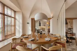 restauracja Muro Rzeszów - okrągły drewniany stół z krzesłami pod białą kopułową lampą