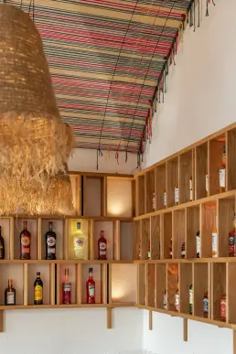 restauracja Muro Rzeszów — detal drewnianych półek barowych z butelkami alkoholi i kolorową peruwiańską tkaniną pod sufitem