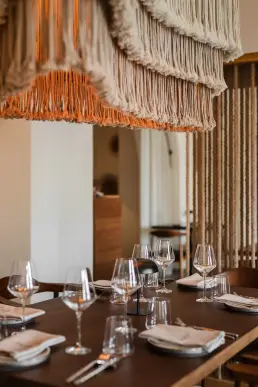 restauracja Muro Rzeszów — detal nakrycia stołu pod makramową lampą z frędzlami i sznurową ścianką działową