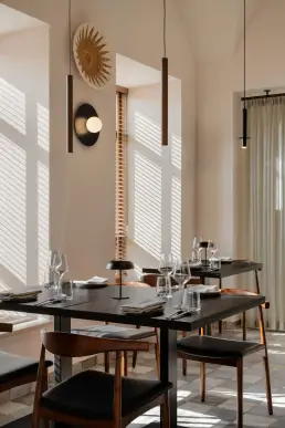 restauracja Muro Rzeszów — ciemne stoliki w naturalnym świetle żaluzji, pleciona dekoracja na ścianie i drewniane lampy wiszące