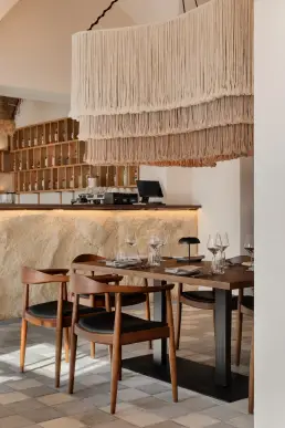 restauracja Muro Rzeszów — stolik przy kamiennym barze pod makramową lampą z frędzlami, drewniane krzesła ze skórzaną tapicerką