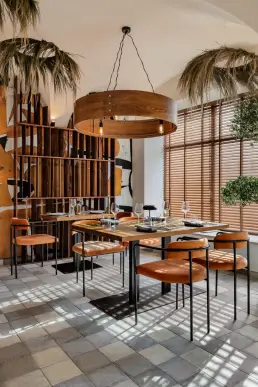 restauracja Muro Rzeszów — sala z pomarańczowymi welwetowymi krzesłami, okrągłą drewnianą lampą i regałem z surowego drewna przy muralu