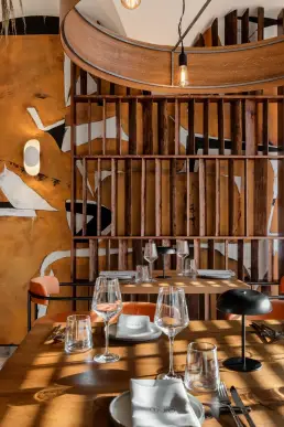 restauracja Muro Rzeszów — detal stolika przy ręcznie malowanym muralu z drewnianym regałem i okrągłą lampą