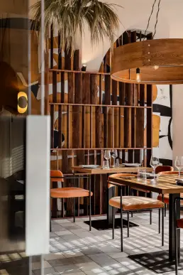 restauracja Muro Rzeszów — widok przez szybę na salę z muralem, pomarańczowymi krzesłami i okrągłą drewnianą lampą