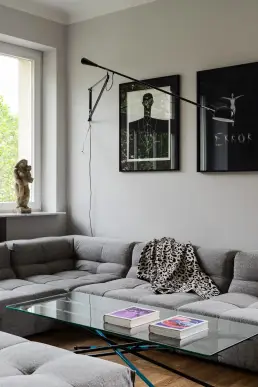 Salon z modułową sofą, galerią obrazów i designerską lampą ścienną