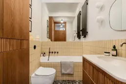 Łazienka z żółtymi płytkami, wanną zabudowaną i podłogą terrazzo