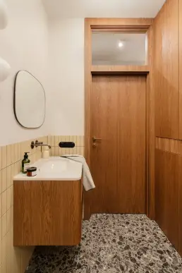Łazienka z dębową szafką, owalnym lustrem i podłogą terrazzo
