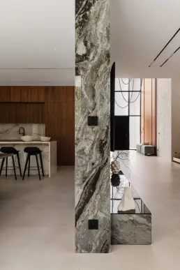 Detal architektoniczny z marmurową kolumną o ekspresyjnym rysunku oddzielającą strefę kuchni od holu wejściowego