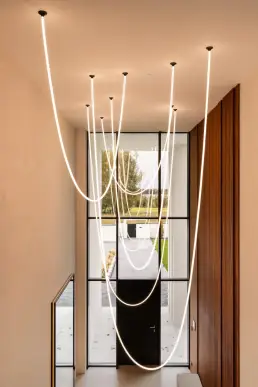 Holl wejściowy z designerską instalacją oświetleniową Flos w formie linii świetlnych zwisających z sufitu