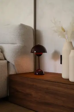Detal sypialni z bordową lampką Flowerpot na drewnianej szafce nocnej i ceramicznymi wazonami z trawą pampasową