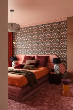 sypialnia z tapetą Williama Morrisa, różowym welurowym łóżkiem i porcelanowymi lampami