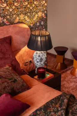 detal szafki nocnej z porcelanową lampą, świecą i kolorowym stolikiem