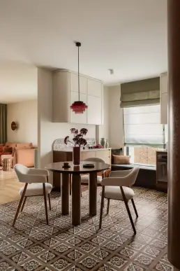 jadalnia z okrągłym stołem, czerwoną lampą retro i widokiem na salon przez kolumnę
